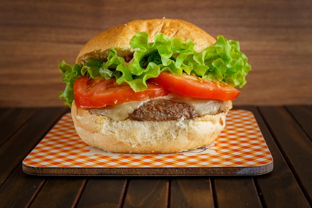 Deliciosa hamburguesa sobre fondo de madera Hamburguesa con tomate, lechuga, carne y queso