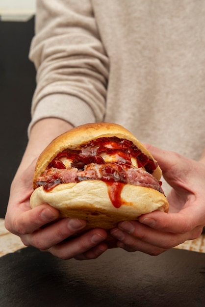 Foto deliciosa hamburguesa de ternera con queso de cabra y mucha mermelada de tomate picante sostenida en dos manos