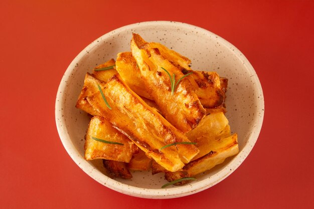 Deliciosa mandioca frita em tigela de cerâmica branca artesanal sobre fundo vermelho Studio