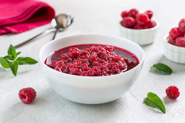 Deliciosa mermelada de frambuesa en un bol sobre un fondo claro Postre tradicional de bayas