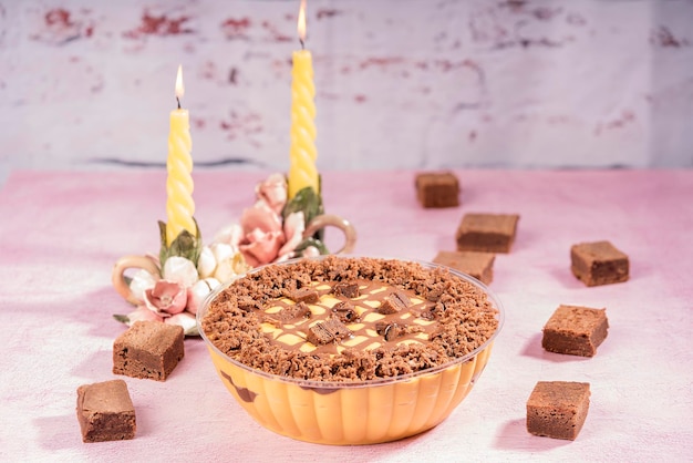 Deliciosa mousse de lucuma com brownies de chocolate, apresentada em mesa com dois candelabros.