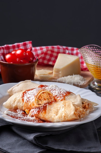 Foto deliciosa panqueca de frango recheada com frango e coberta com molho de tomate e queijo parmesão