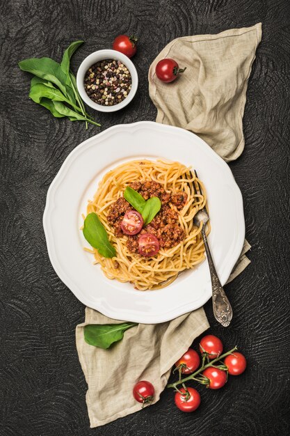 Deliciosa pasta italiana clásica boloñesa con tomates en un plato sobre un fondo oscuro.