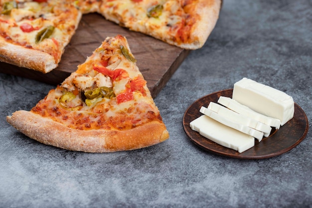 Deliciosa pizza caliente en rodajas con queso en rodajas colocado sobre una mesa de piedra.