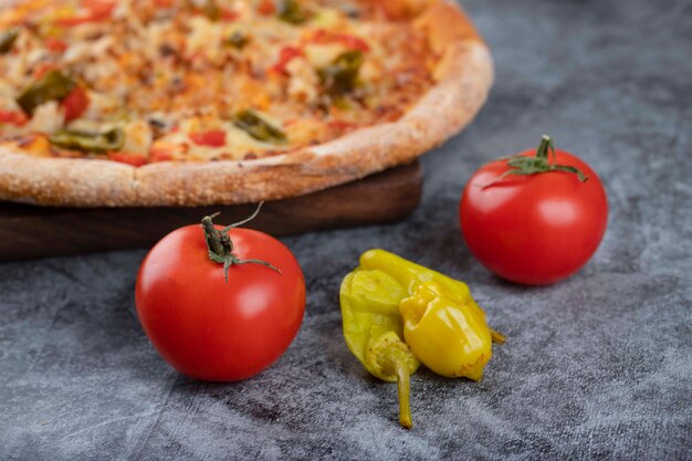 Deliciosa pizza caliente en rodajas con tomates rojos frescos colocados sobre una mesa de piedra.