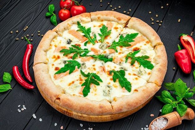 Deliciosa pizza caliente con rúcula de salmón y diferentes especias en mesa de madera lista para comer