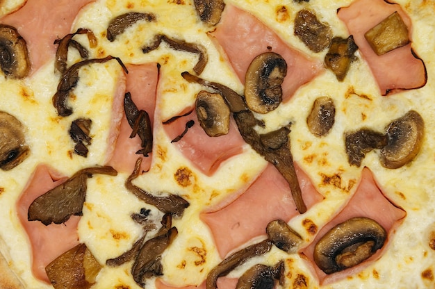 Deliciosa pizza com presunto e cogumelos em uma tábua