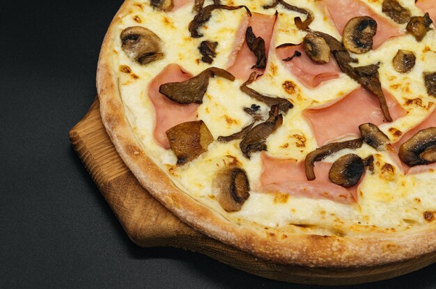 Deliciosa pizza com presunto e cogumelos em uma tábua