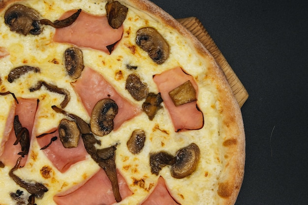 Deliciosa pizza com presunto e cogumelos em uma tábua
