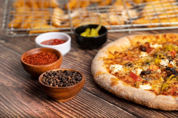 Deliciosa pizza com queijo e legumes frescos na mesa de madeira.