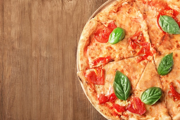 Deliciosa pizza com tomate e manjericão fresco em fundo de madeira