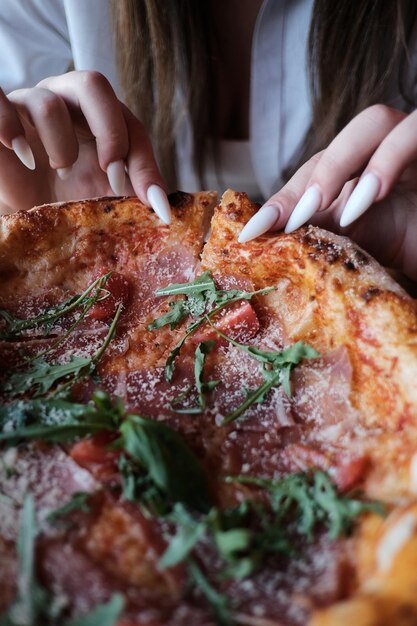 Deliciosa pizza de presunto com queijo tomate e rúcula na mesa de madeira