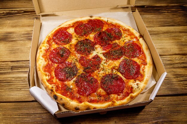 Deliciosa pizza fresca en caja de cartón sobre una mesa de madera Concepto de entrega a domicilio de comida comida rápida entrega de pizza