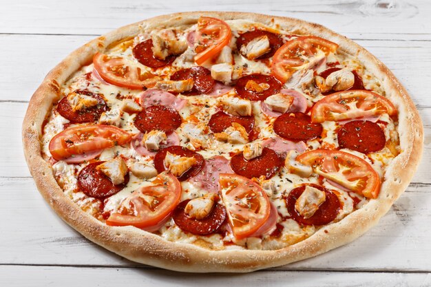 Deliciosa pizza fresca com frango presunto tomate servido na mesa de madeira