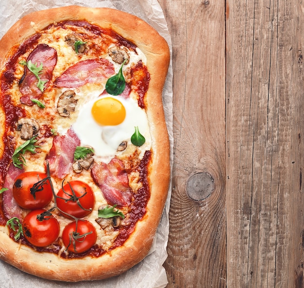 Deliciosa pizza fresca del horno con huevo, jamón serrano y tomate