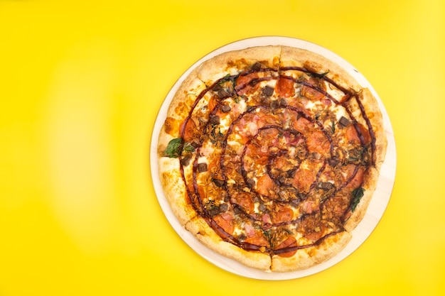 Deliciosa pizza grande com bacon e espinafre em um fundo amarelo