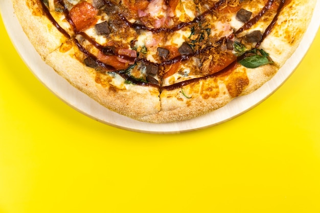 Deliciosa pizza grande con tocino y espinacas sobre un fondo amarillo.