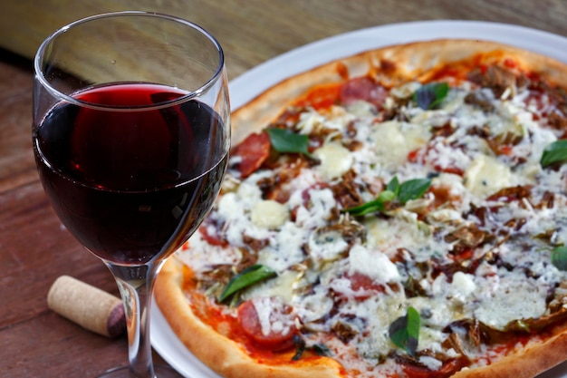 Foto deliciosa pizza italiana com taça de vinho tinto