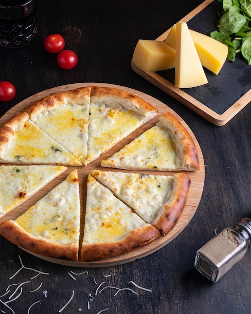 Deliciosa pizza italiana cuatro quesos con tomates de albahaca y aceite de oliva en una mesa de madera vertical