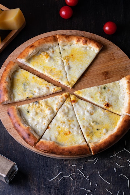 Deliciosa pizza italiana de cuatro quesos con tomates Basil y aceite de oliva en una mesa de madera Vertical