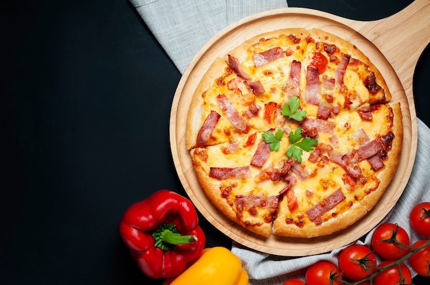 Deliciosa pizza italiana fatiado presunto, bacon e queijo com ingredientes alimentares na cozinha velha