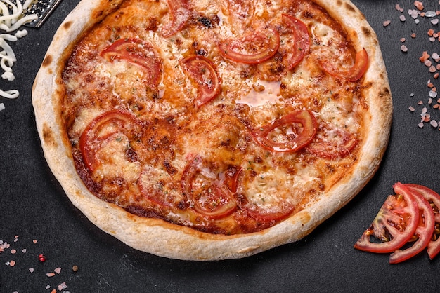Deliciosa pizza italiana fresca com cogumelos e tomate em um fundo escuro de concreto. cozinha italiana