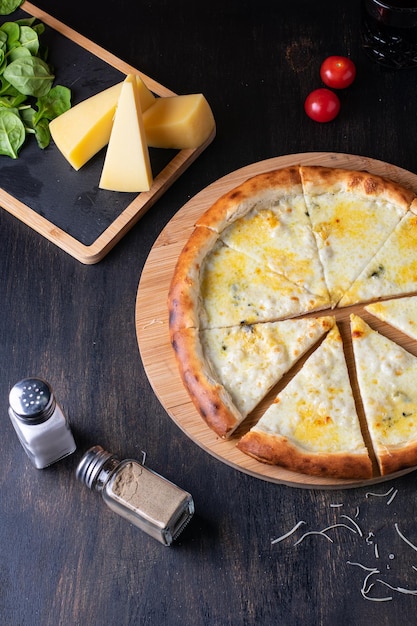 Deliciosa pizza italiana quatro queijos com tomate manjericão e azeite em uma mesa de madeira plana