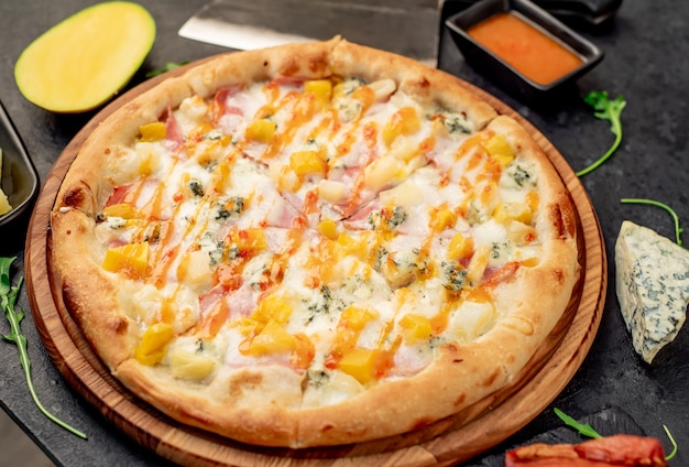 Deliciosa pizza con jamón, queso, piña, mango sobre un fondo de piedra