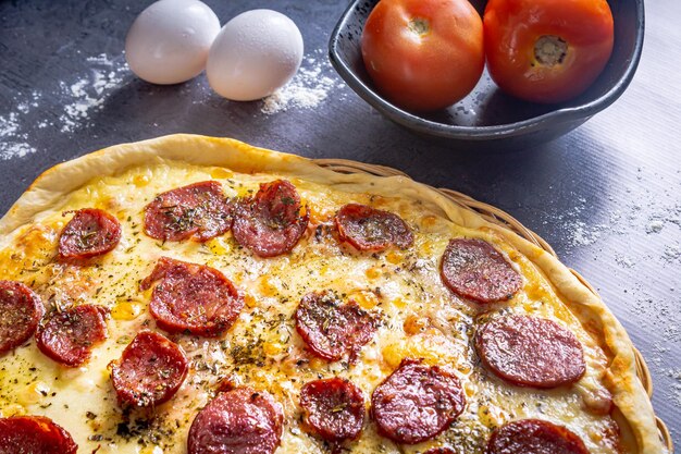 Deliciosa pizza de pepperoni con huevos, trigo, ajo, tomate y queso sobre fondo oscuro