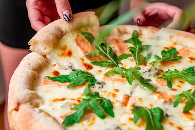 Deliciosa pizza quente com rúcula de salmão e especiarias diferentes na mesa de madeira pronta para comer