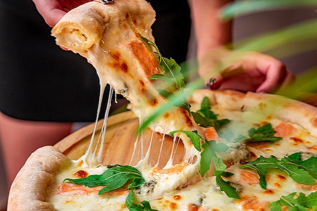 Deliciosa pizza quente com rúcula de salmão e especiarias diferentes na mesa de madeira pronta para comer