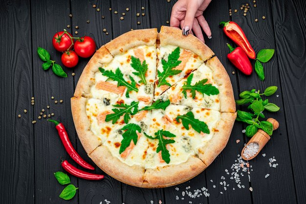 Deliciosa pizza quente com rúcula de salmão e especiarias diferentes na mesa de madeira pronta para comer