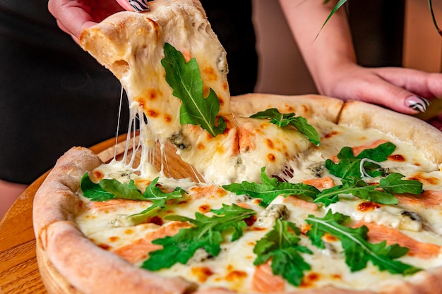 Deliciosa pizza quente com rúcula de salmão e especiarias diferentes na mesa de madeira pronta para comer