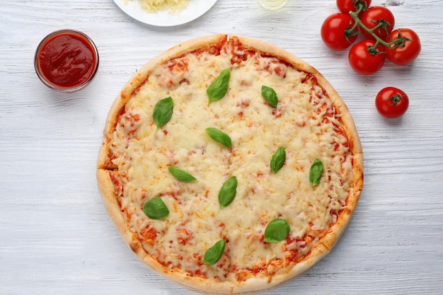 Deliciosa pizza con queso derretido y albahaca sobre mesa de madera