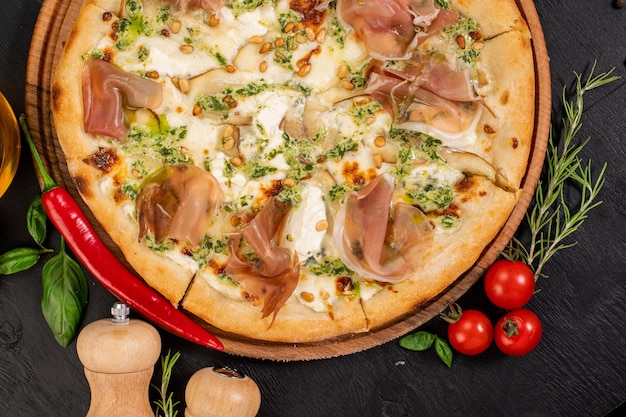 Deliciosa pizza con queso philadelphia y jamón sobre fondo de madera