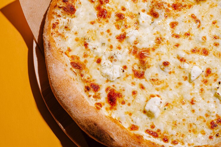 Deliciosa pizza de queso recién horneada servida en una bandeja de madera con un fondo amarillo brillante