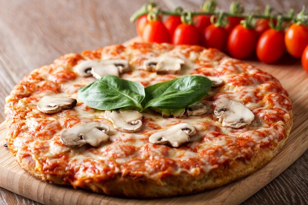 Deliciosa pizza recién horneada con tomate, queso mozzarella, champiñones y albahaca fresca