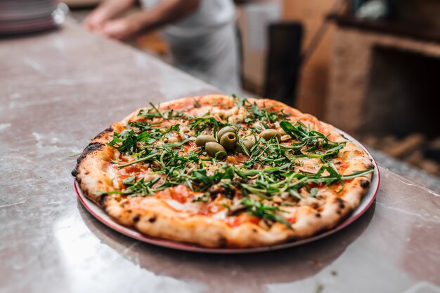 Deliciosa pizza con rúcula y aceitunas.