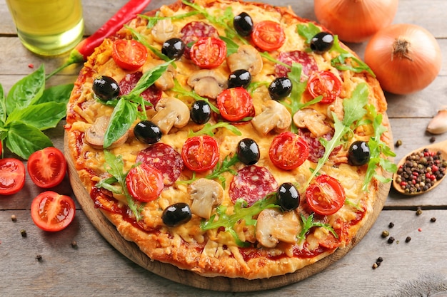 Deliciosa pizza sabrosa con ingredientes en la mesa de madera