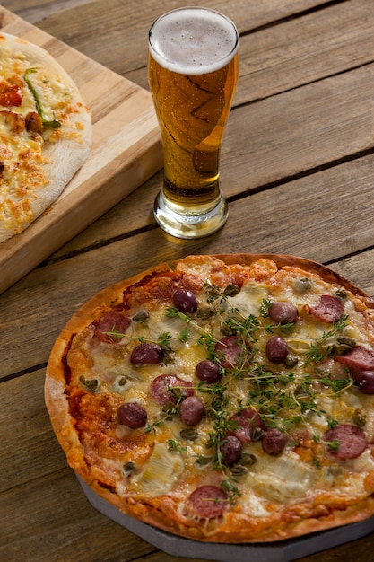 Deliciosa pizza servida sobre tabla de madera con un vaso de cerveza