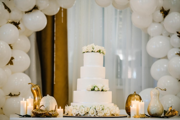 Deliciosa recepción de boda Pastel sobre un fondo globos Mesa decorada para boda Globos blancos velas hojas de otoño y calabazas Ubicación de otoño y decoración de Halloween Fiesta de cumpleaños