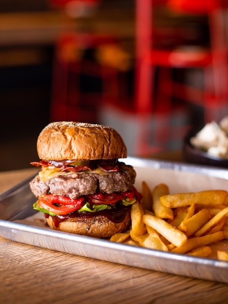 Deliciosa y sabrosa hamburguesa casera a la parrilla con carne, queso, tocino y salsa en la mesa de madera