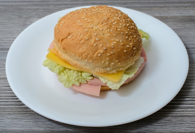 Deliciosa sabrosa hamburguesa con queso y salchichas en la placa blanca.