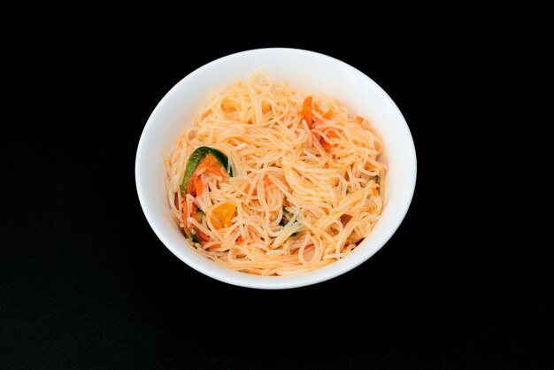 Deliciosa salada asiática funchose em tigela branca sobre fundo preto Foco seletivo Conceito de comida asiática