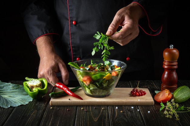 Deliciosa salada de legumes pelas mãos do chef O conceito de menu ou receita para um hotel em um fundo escuro