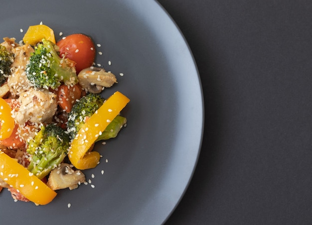 Deliciosa salada feita de brócolis, tomate cereja, pimenta amarela, cogumelos, pedaços de peito de frango e sementes de gergelim