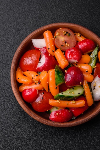 Deliciosa salada fresca e suculenta com rabanetos tomates cenouras pepinos especiarias e ervas num fundo de concreto escuro