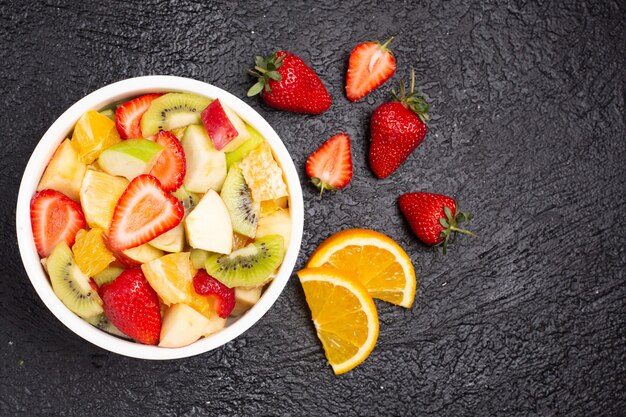 Deliciosa salada mista de frutas frescas na mesa preta