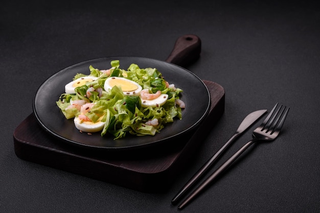 Deliciosa salada saudável fresca com alface de ovo de camarão e sementes de linho em uma placa de cerâmica preta sobre um fundo de concreto