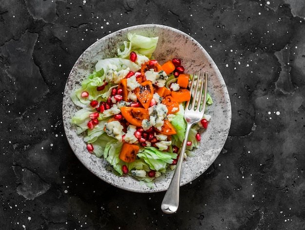 Deliciosa salada sazonal com iceberg de romã gorgonzola de abóbora em uma vista superior de fundo escuro